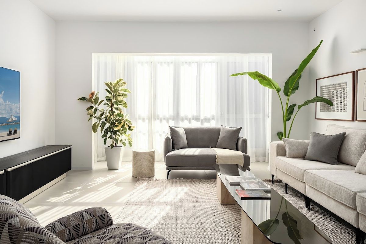 Una sala de estar moderna con un sofá gris, una mesa de centro y una planta grande.