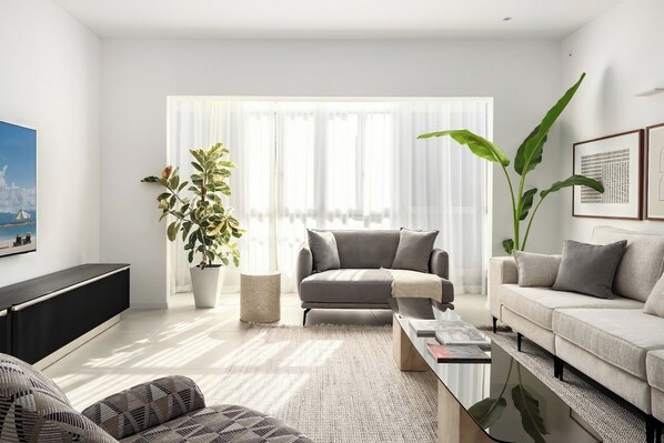 A modern living room with a grey sofa, a coffee table, and a large plant.