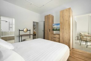 Una camera da letto moderna con un letto grande, un'armadio in legno e un angolo ristoro con tavolo e sedie.