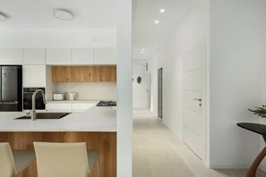 A modern kitchen with white cabinetry, a wooden countertop, and a black refrigerator. - Central 3BR Designer Escape by SeaNRent (Tel Aviv-Yafo)