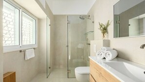 Et moderne badeværelse med brusekabine i glas, toilet i hvidt og et vaskeområde med spejl.