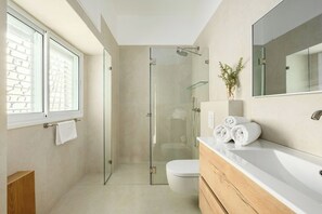 Un bagno moderno con box doccia in vetro, un water bianco e un lavabo con specchio.