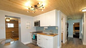 A modern kitchen with white cabinets, a stainless steel stove, and a microwave. - CC62-Davis Cottage, Walk to shops! Firepit! Pets Ok! A/C (Davis)