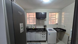 A compact kitchen with a refrigerator, stove, sink, and a washing machine. - Beautiful Apartment Near VG Shopping Mall (Várzea Grande)