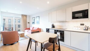 A modern kitchen with white cabinets, a Bosch microwave, and a kettle on the counter. - Stylish One-Bed Retreat (London)