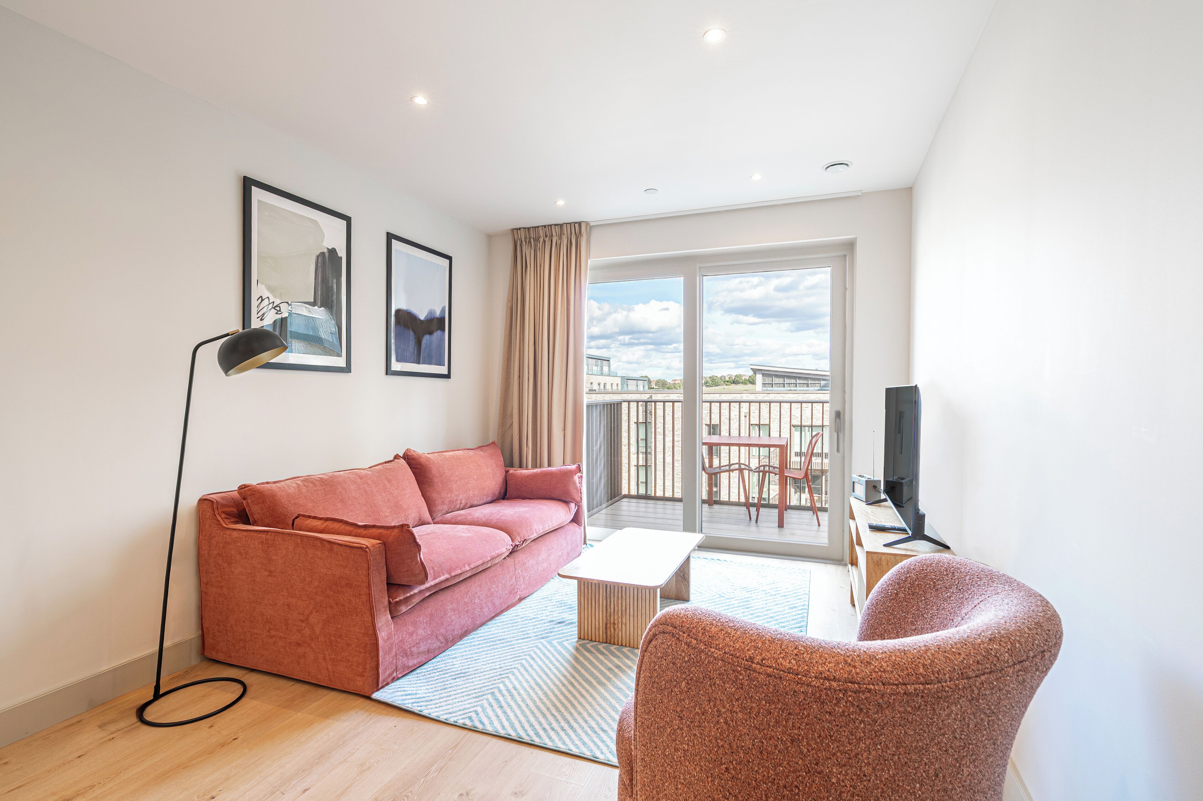 A modern living room with a sofa, armchair, and a flat-screen TV.