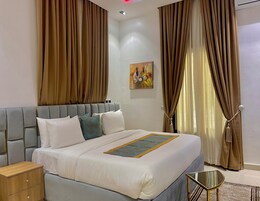 Quarto de hotel moderno com uma cama grande, uma mesinha de cabeceira e uma pequena mesa lateral.