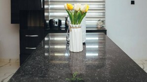 A kitchen counter with a white vase containing yellow and white tulips. - The Olive Place (Jos)