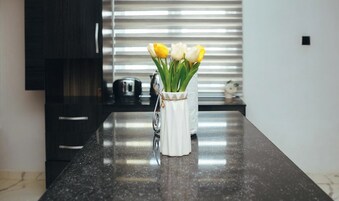 Uma bancada de cozinha com um vaso branco contendo tulipas amarelas e brancas.