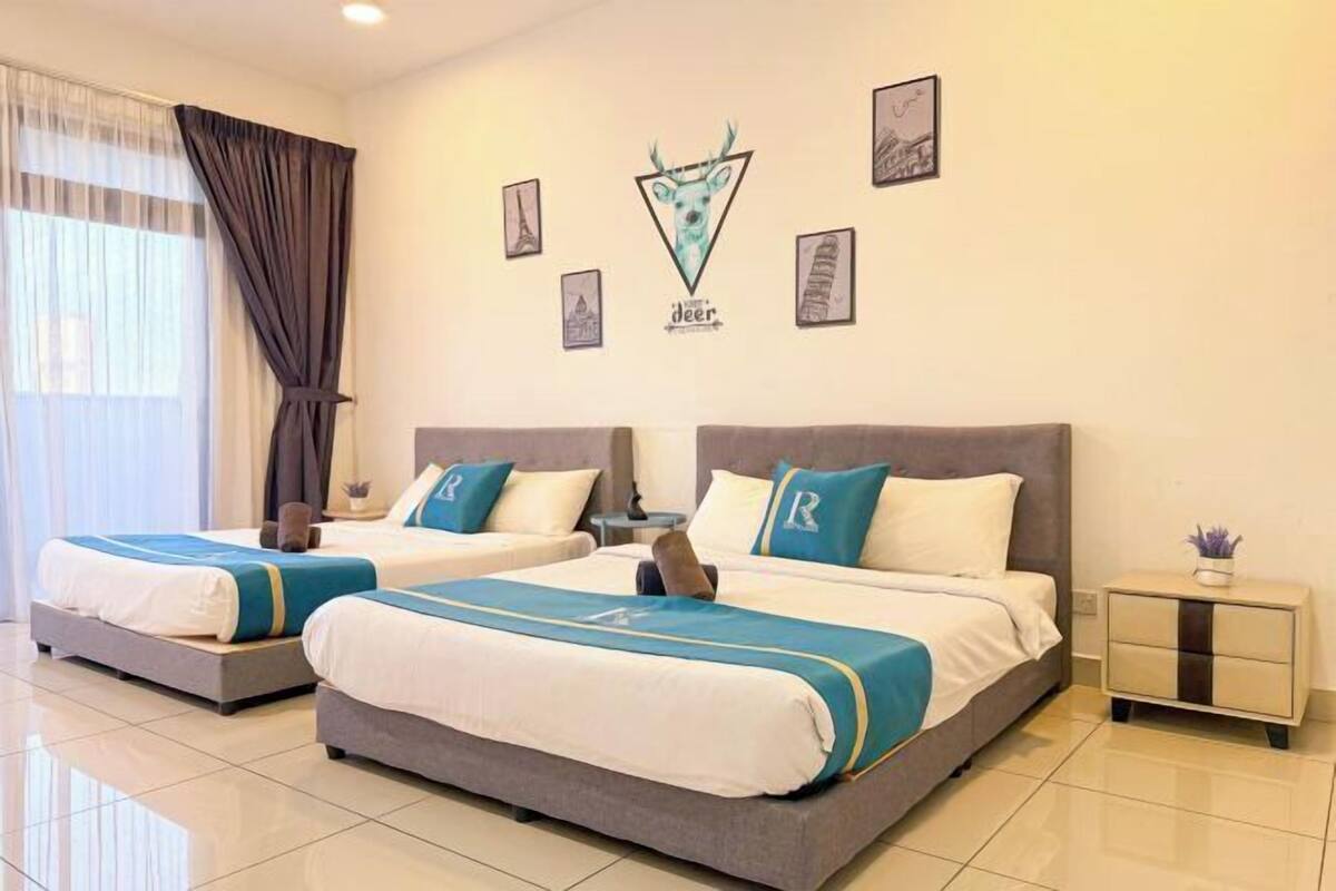 Habitación de hotel con dos camas, una mesita de noche, una pequeña mesa y una ventana con cortinas.
