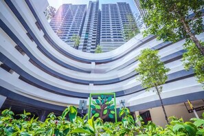 Un edificio moderno con balcones curvos y una escultura de árbol verde en el centro.