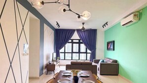 Un comedor con una mesa preparada para cuatro personas, un sofá y una ventana con cortinas.
