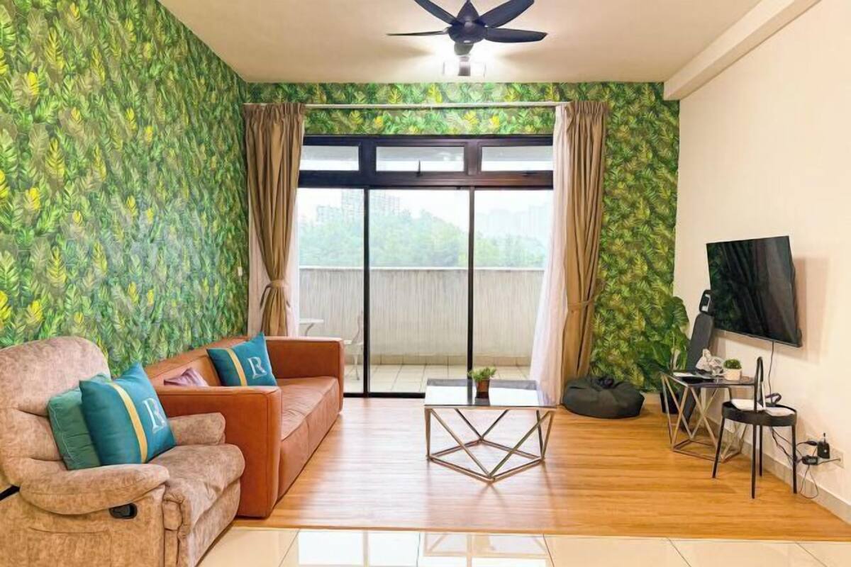 Una sala de estar con un sofá, una mesa de centro, un televisor y un balcón con cortinas.