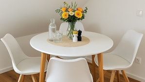 A round white table with a vase of flowers, two glasses, and a water bottle. - Fischerstübchen (7) Dat Fischerhuus Between the Baltic Sea and directly at the harbor (Pruchten)