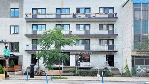 A multi-story building with a sign for 'MODE DES ONGLES SPA' on the ground floor. - Central 2BR | Near Metro & Parks (Montréal)