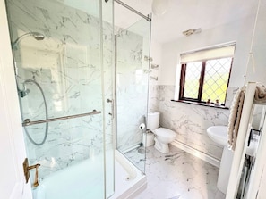Et moderne badeværelse med en glasafskærmet brusekabine, toilet og håndvask.