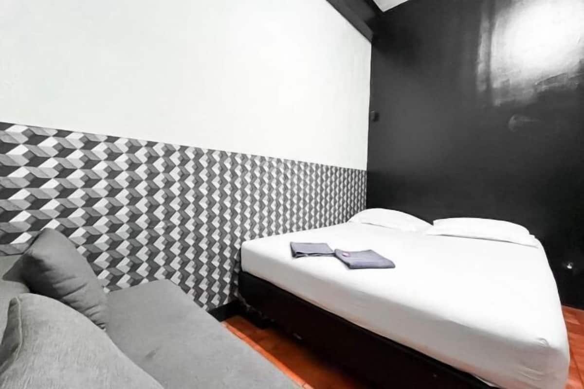 A room with a bed, a sofa, a patterned wall, and a black painted wall.