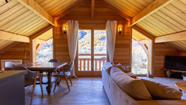 Une cabane en bois comprenant un coin repas, un canapé et un téléviseur.