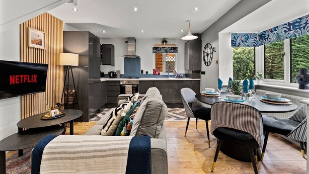 Un salon moderne comprenant un canapé, un téléviseur et un coin repas avec des chaises et une table.