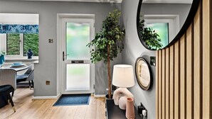 Un intérieur moderne comprenant un coin repas, un grand miroir, une plante en pot et une lampe.