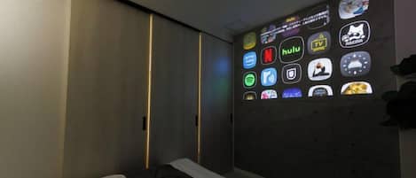 Un dormitorio con cama, un televisor empotrado mostrando varios iconos de aplicaciones y una puerta corrediza.