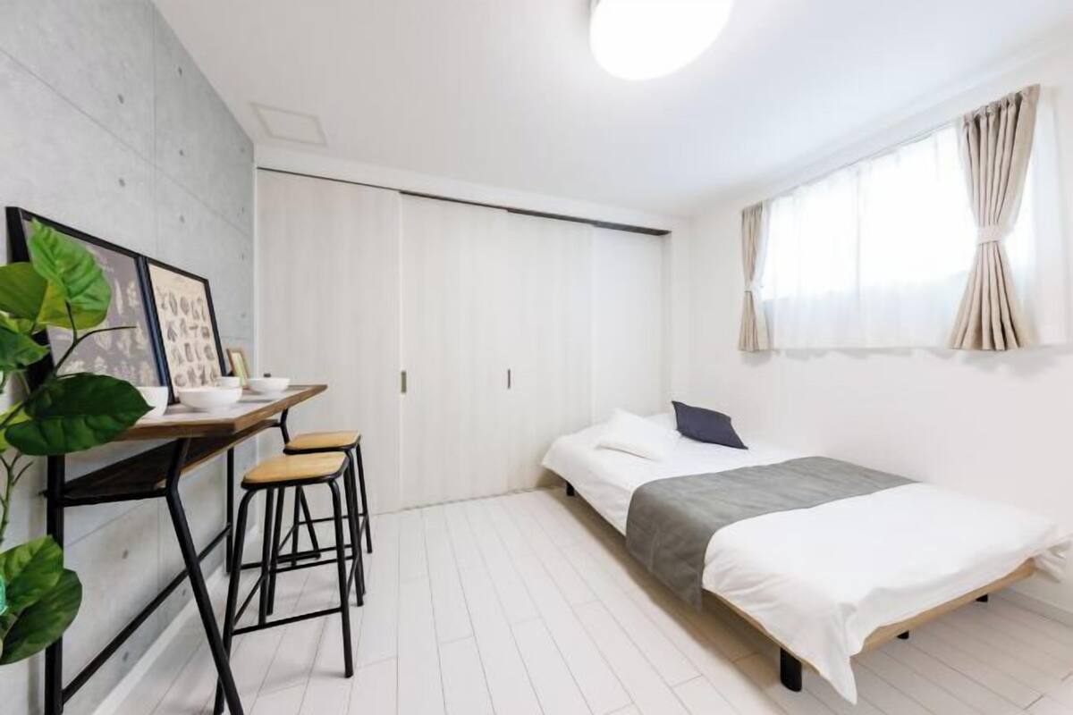 A minimalist bedroom with a bed, a desk, and a chair.
