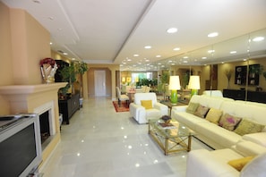 A modern living room with a fireplace, white sofas, a coffee table, and a TV.