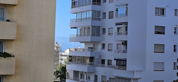 A multi-story residential building with balconies, large windows, and a clear sky.