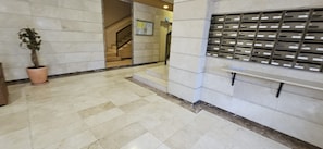 A lobby with a tiled floor, a staircase, a potted plant, and a wall-mounted mailbox.