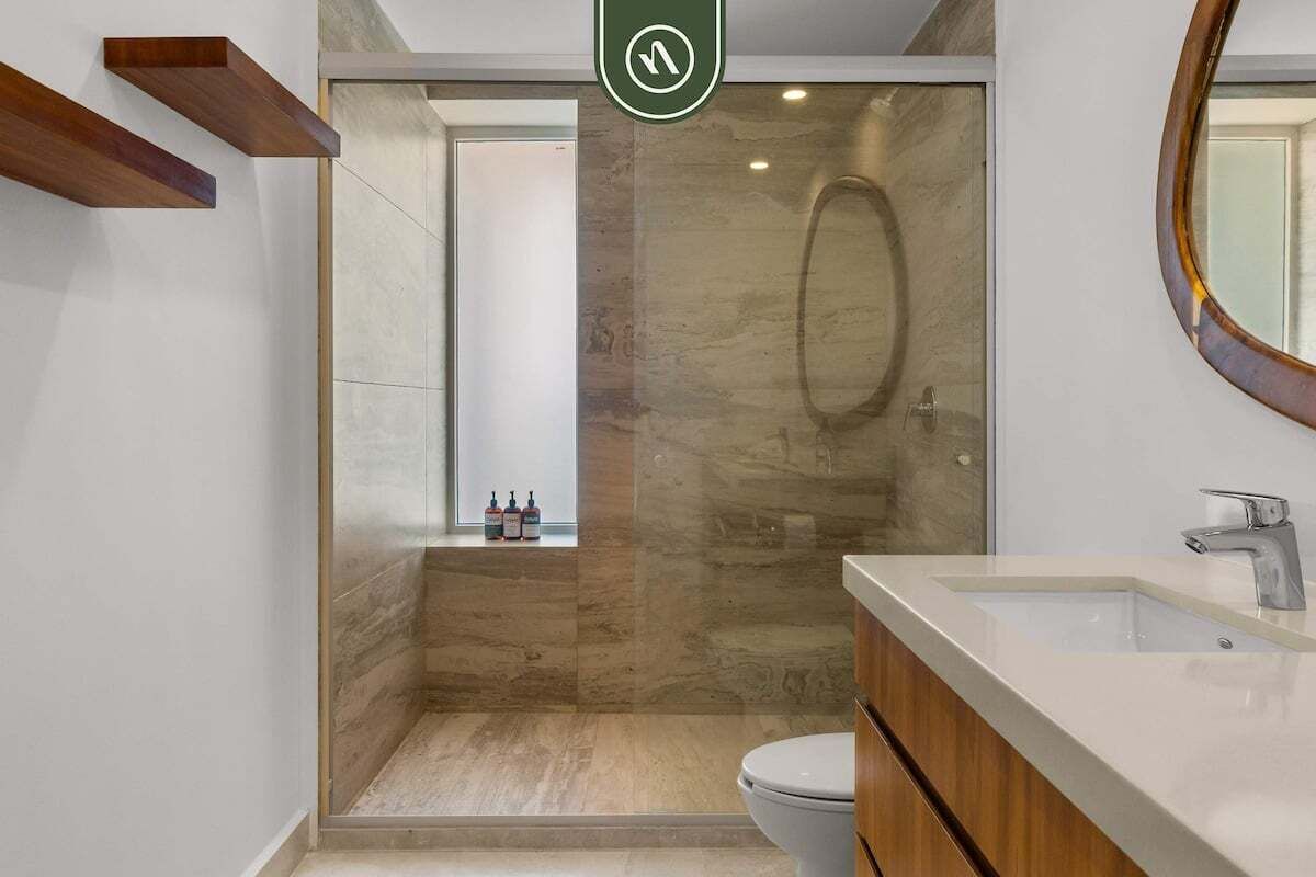 A modern bathroom with a glass-enclosed shower, a white sink, and a wooden vanity.