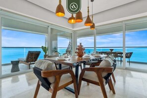 A dining area with a large table, chairs, and a view of the ocean.