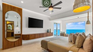 A modern bedroom with a bed, a TV mounted on the wall, a ceiling fan, and a view of the ocean. - Luxury 4 BR Condo Amazing Views - Beach - Pools (Puerto Vallarta)