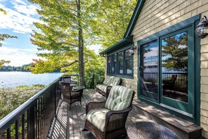 Una terraza con mobiliario de mimbre y vista a un lago.