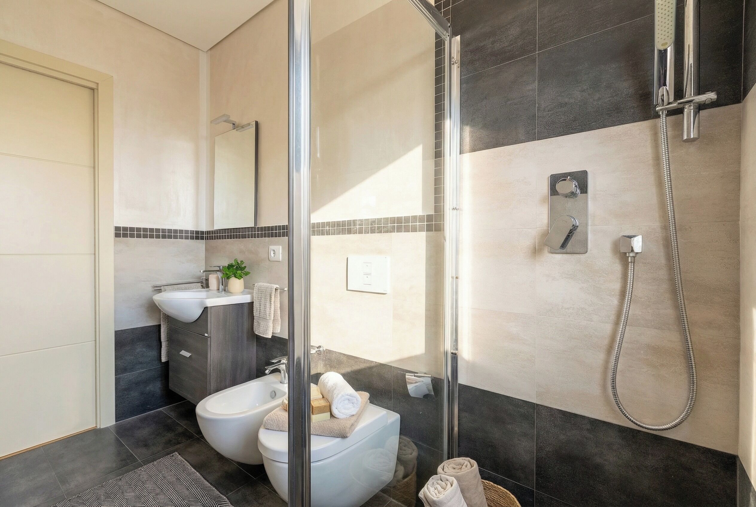 Een moderne badkamer met een douchecabine van glas, een toiletbrons, een wastafel en een toilet.