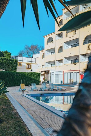 A multi-story hotel with a swimming pool, outdoor seating, and a well-maintained garden. - EiraSol by Umbral (Albufeira)