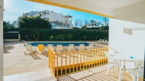 A modern outdoor pool area with a wooden deck, white lounge chairs, and a yellow railing. - EiraSol by Umbral (Albufeira)