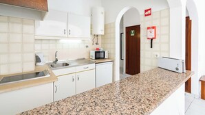 A modern kitchen with white cabinets, granite countertops, a built-in microwave, and a water heater. - EiraSol by Umbral (Albufeira)