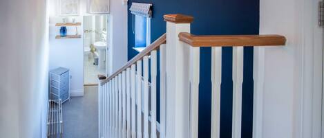 A staircase with white balusters and a wooden handrail leading to a room with a blue accent wall.