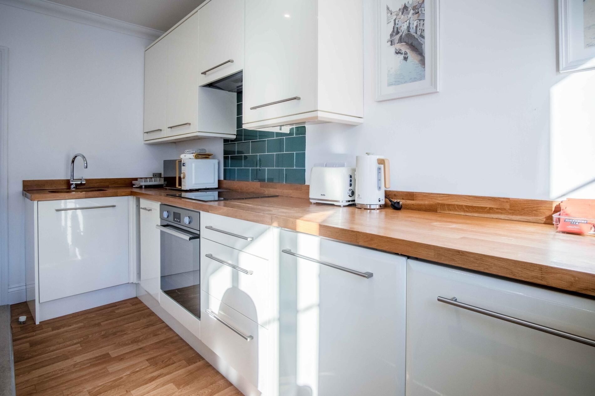 A modern kitchen with white cabinets, a wooden countertop, and a built-in oven.
