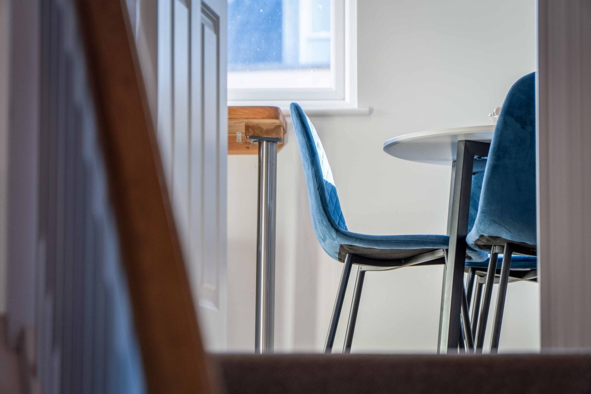 A dining area with a table and chairs, a window, and a wooden door frame.