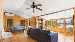Een houten cabin interieur met een bank, een stoel, een tafel en een plafondventilator.