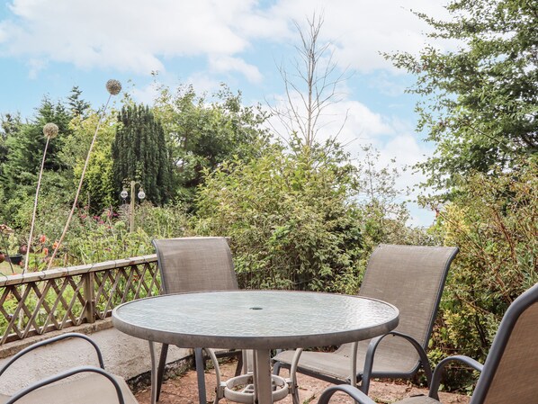 An outdoor patio with a round metal table and two chairs.