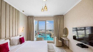 Une chambre d’hôtel moderne dotée d’un grand lit, d’une télévision, d’un bureau et offrant une vue sur le paysage urbain et la piscine.
