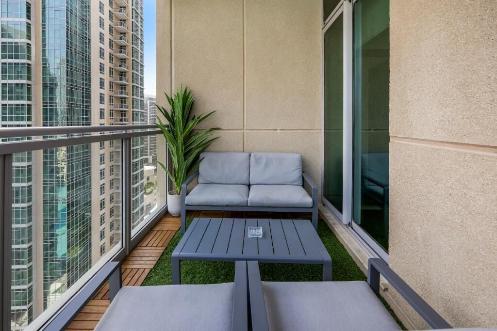 Un balcon avec un canapé gris, une petite table et une plante en pot.
