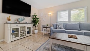 Een woonkamer met een televisie, een bank, een salontafel, een kast en een plant in pot.