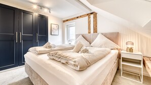 A bedroom with a large bed, a nightstand, and dark wooden wardrobes. - Ferienwohnung Alpen Zentral (Bludenz)