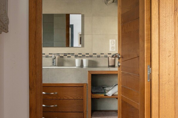 Een badkamer met een houten wastafelmeubel, een spiegel, een wastafel en een handdoekhouder.