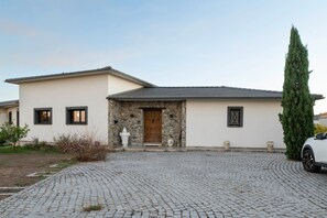 A modern house with a stone facade, a wooden door, and a cobblestone driveway. - Bed and Breakfast 'Chambre 1' with Mountain View, Shared Pool and Wi-Fi (Aléria)