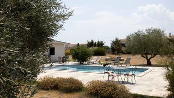 Une piscine avec des chaises longues et un petit espace patio.