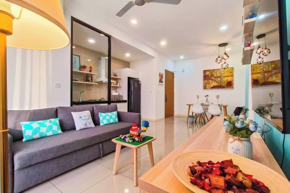 Una sala de estar moderna con un sofá, una mesita con juguetes, una mesa de comedor de madera y una cocina al fondo.